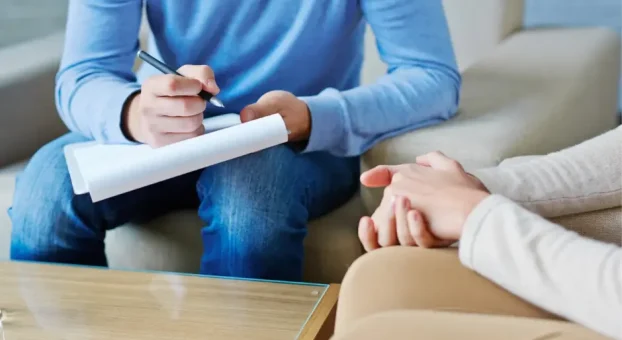 Individual_supervision_1 Therapist taking notes while speaking with a client.