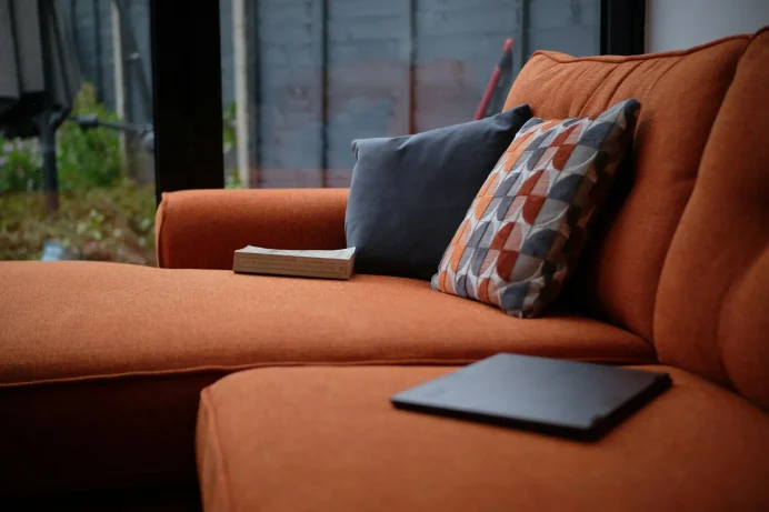 sean-robbins-WZmC86GFdZw-unsplash Cozy sofa with cushions and a laptop nearby.